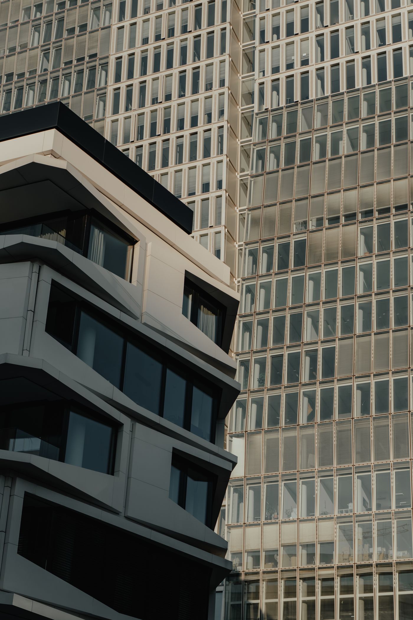 Modernes Gebäude vor Glasfassade eines Hochhauses